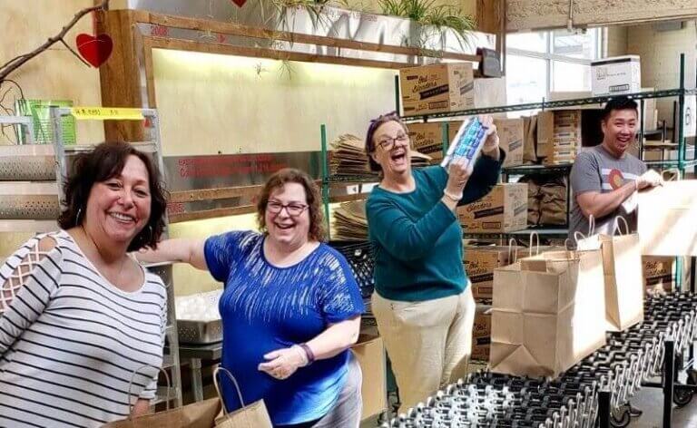 Gina Torres, Project Angel Heart volunteer with friends packing meals for clients