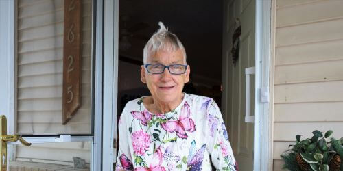 Client Cheryl smiling in front of her door