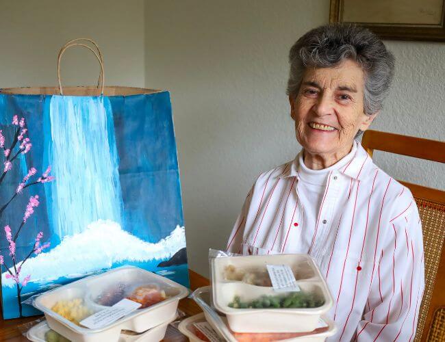 Carol smiling with Project Angel Heart meals