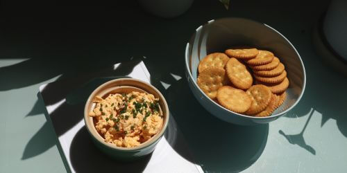 Bowl of pimento cheese next to bowl of crackers