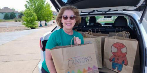 Loralee holding meal bag in front of car