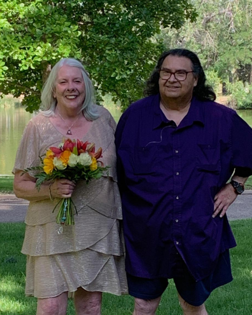 Project Angel Heart volunteer holding a bouquet of flowers with her husband standing to her left.