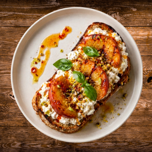 Plate of a grilled peach and Burrata toast on a wooden table.